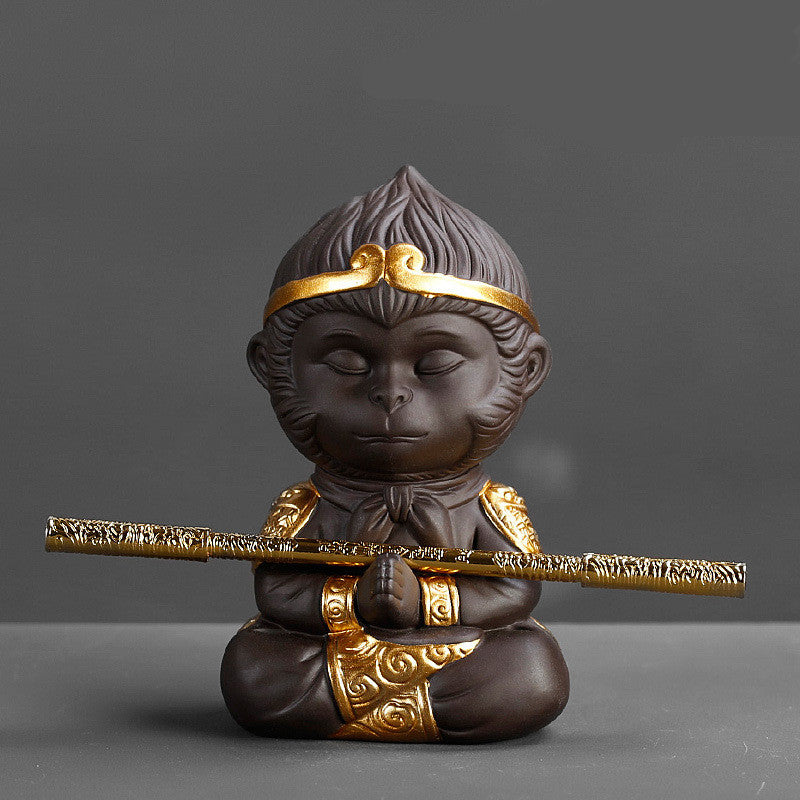 Statue of a monkey with gold accents holding a staff on a gray background