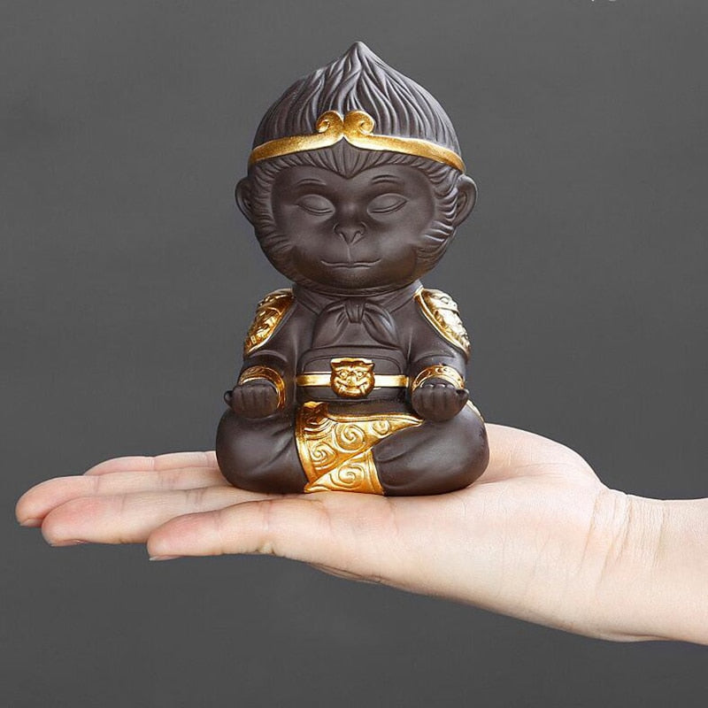 Small monkey figurine with gold accents held in a hand against a dark background