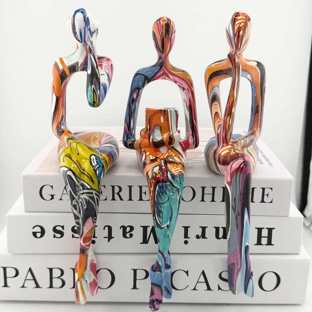 Minimalist colorful resin sculpture of three seated figures for modern home décor
