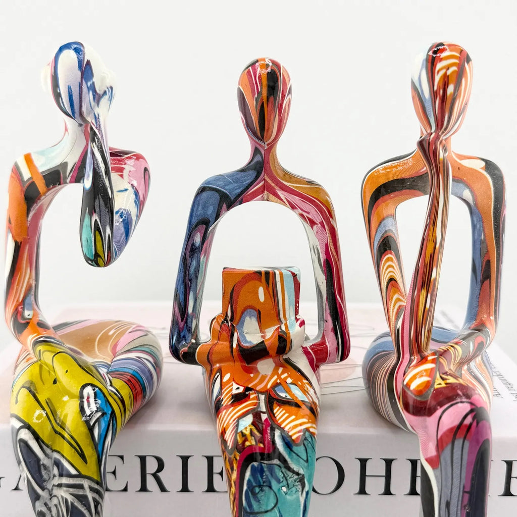 Minimalist colorful resin sculpture of three seated figures for modern home décor
