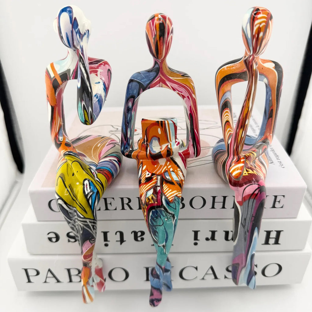 Minimalist colorful resin sculpture of three seated figures for modern home décor
