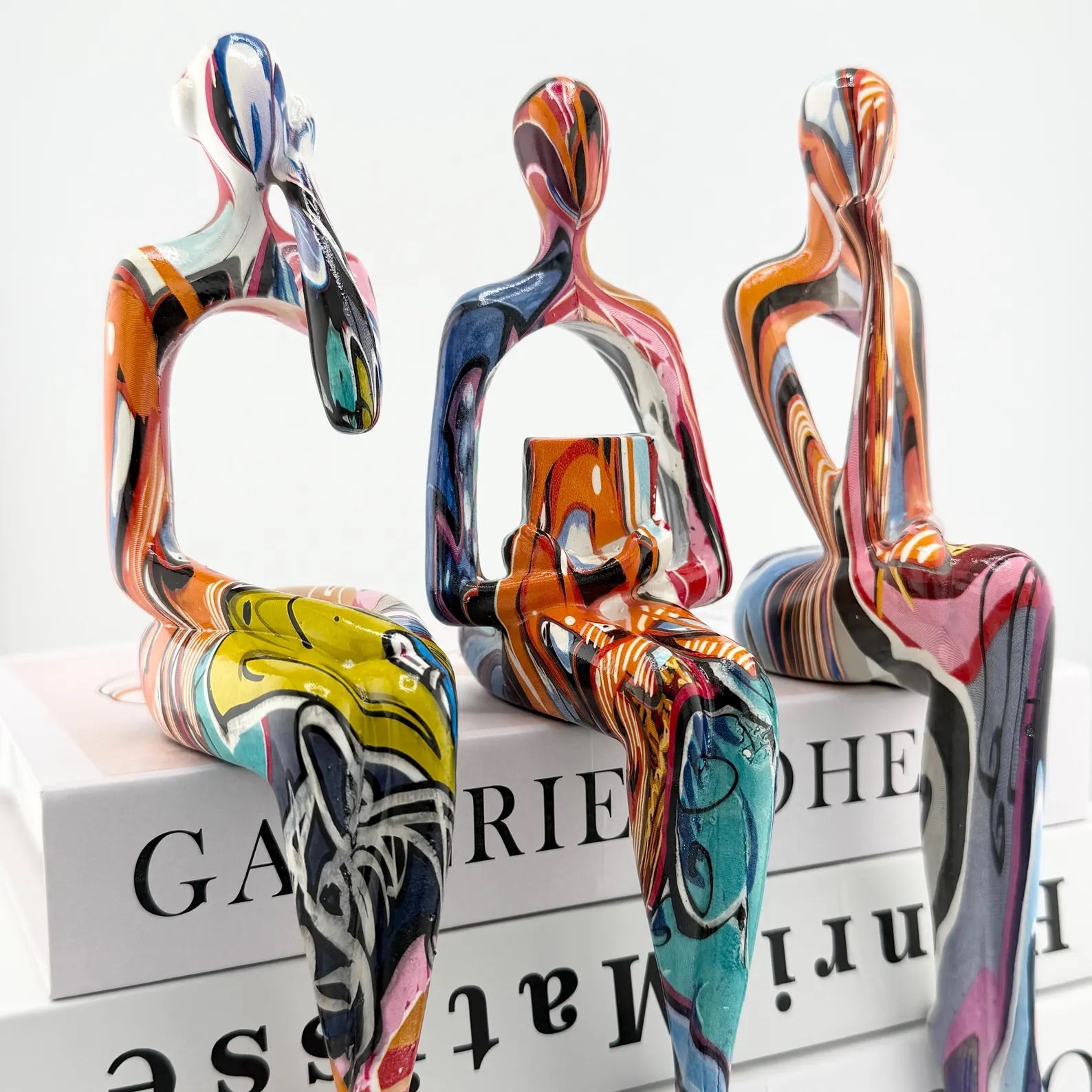 Minimalist colorful resin sculpture of three seated figures for modern home décor
