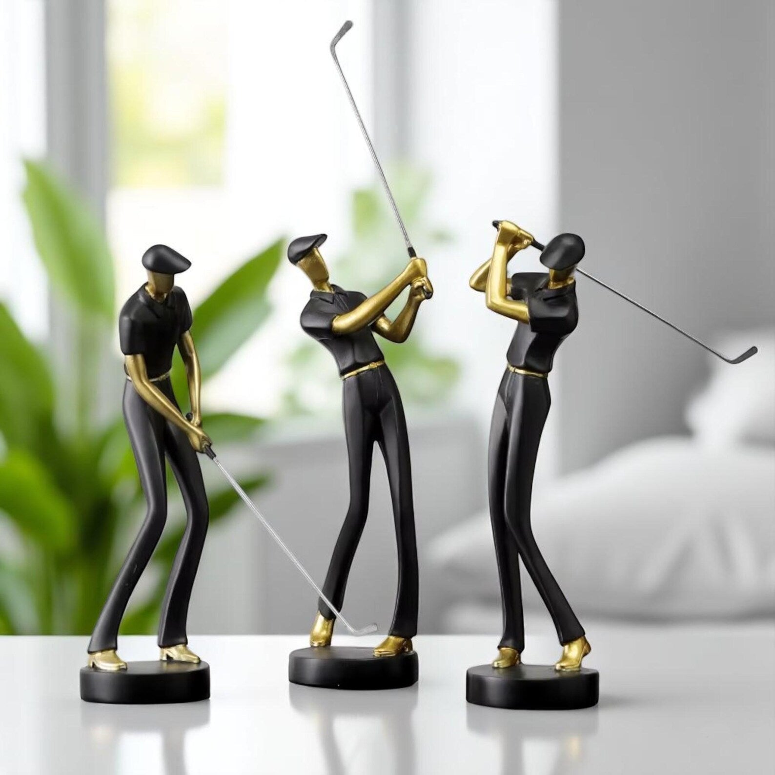 Three golf-themed figurines on a white surface with a blurred indoor background